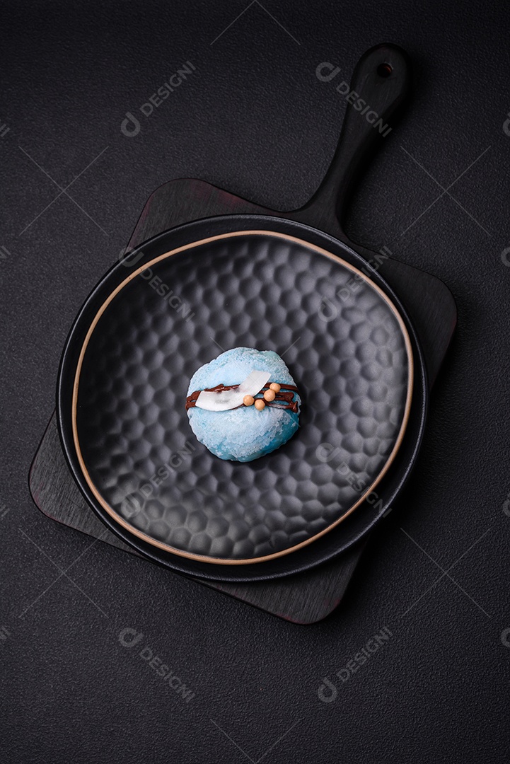 Deliciosas sobremesas mochi coloridas ou sorvete com massa de arroz e coberturas sobre um fundo escuro de concreto