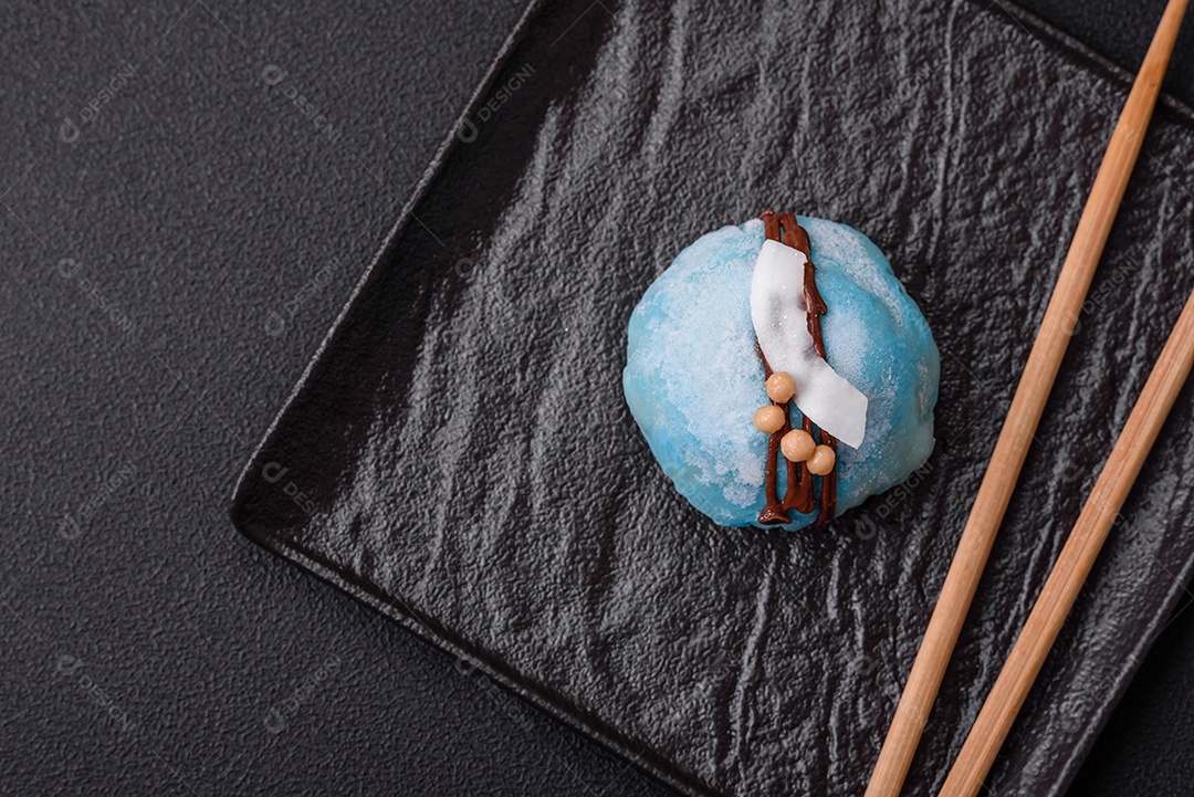 Deliciosas sobremesas mochi coloridas ou sorvete com massa de arroz e coberturas sobre um fundo escuro de concreto