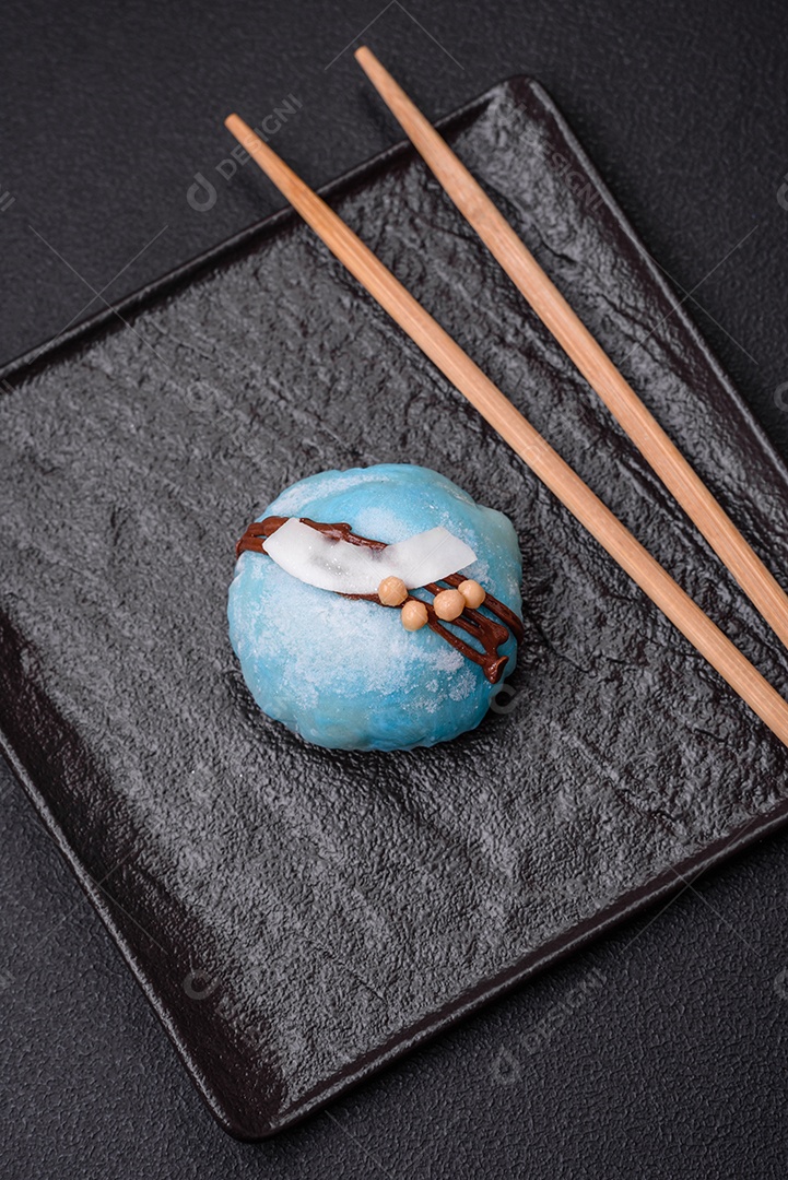 Deliciosas sobremesas mochi coloridas ou sorvete com massa de arroz e coberturas sobre um fundo escuro de concreto