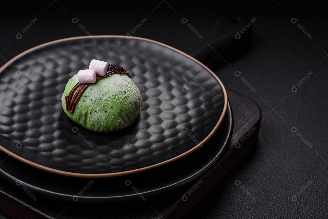 Deliciosas sobremesas mochi coloridas ou sorvete com massa de arroz e coberturas sobre um fundo escuro de concreto