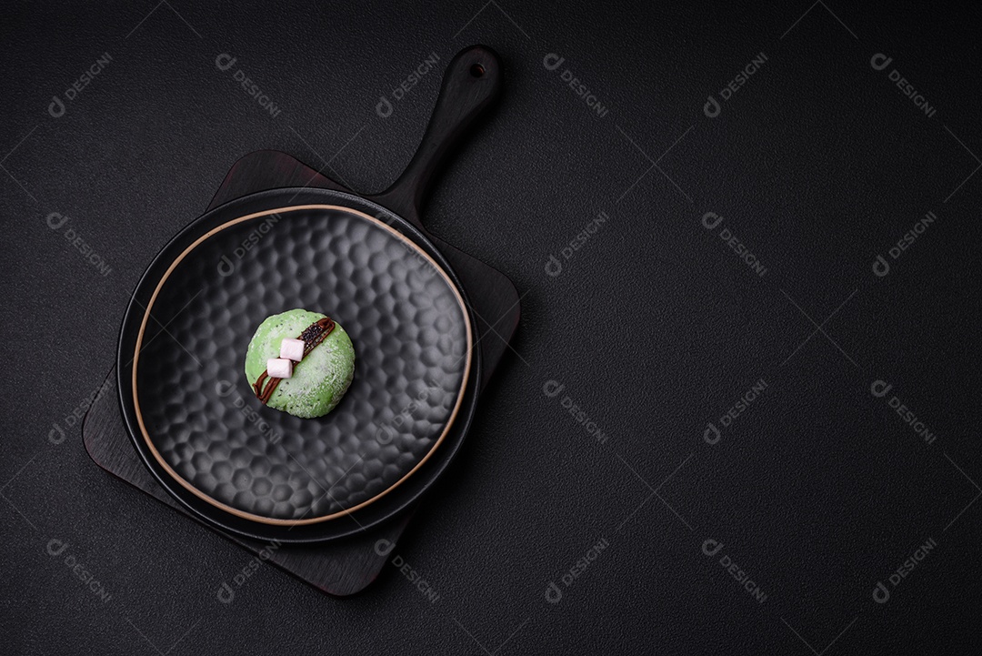 Deliciosas sobremesas mochi coloridas ou sorvete com massa de arroz e coberturas sobre um fundo escuro de concreto