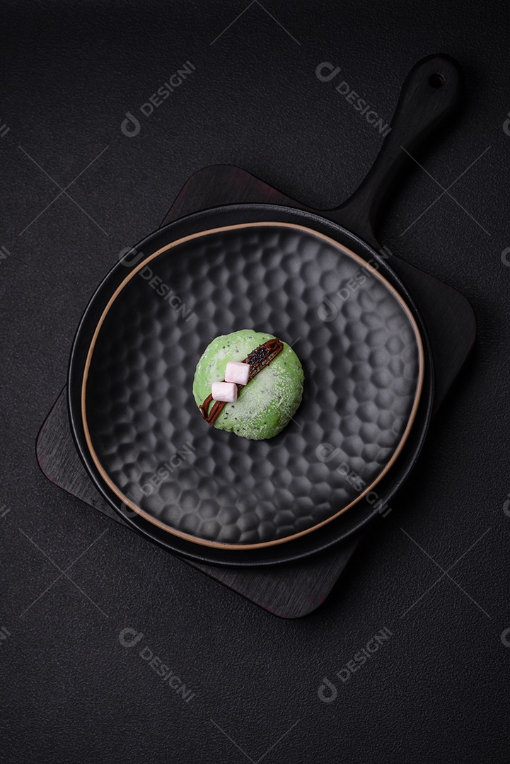 Deliciosas sobremesas mochi coloridas ou sorvete com massa de arroz e coberturas sobre um fundo escuro de concreto