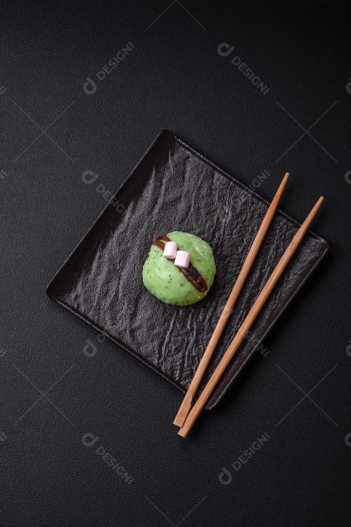 Deliciosas sobremesas mochi coloridas ou sorvete com massa de arroz e coberturas sobre um fundo escuro de concreto