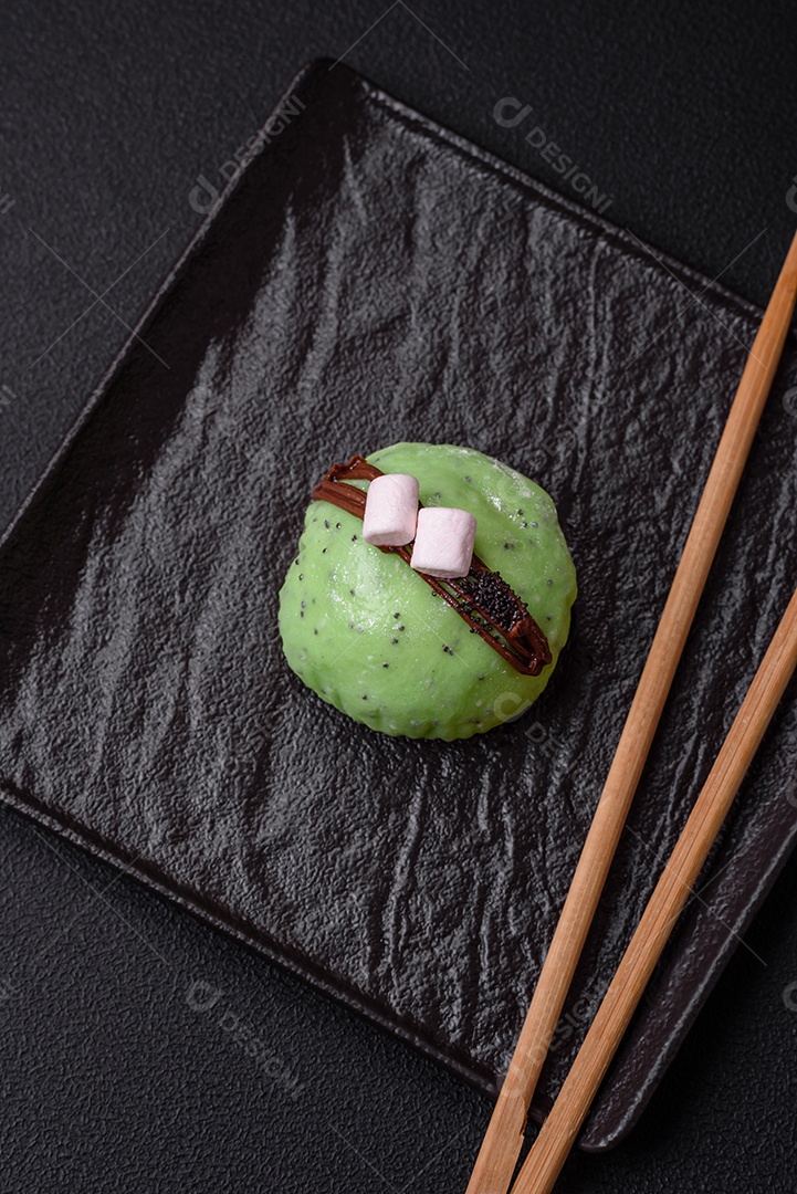 Deliciosas sobremesas mochi coloridas ou sorvete com massa de arroz e coberturas sobre um fundo escuro de concreto