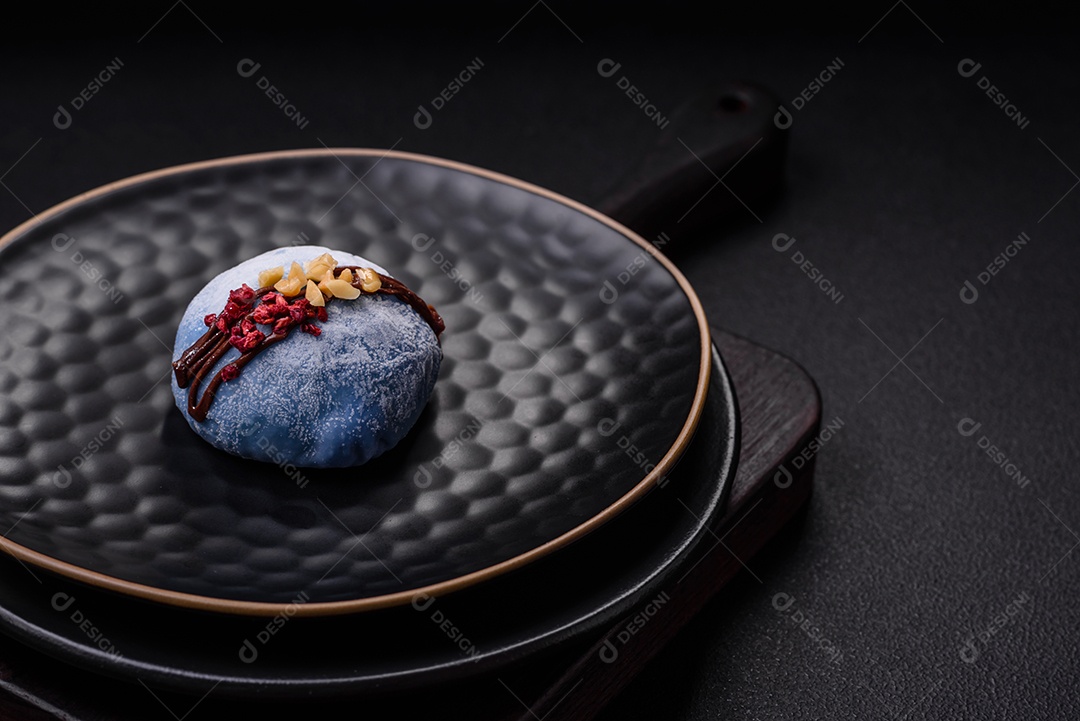 Deliciosas sobremesas mochi coloridas ou sorvete com massa de arroz e coberturas sobre um fundo escuro de concreto