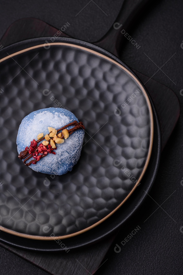 Deliciosas sobremesas mochi coloridas ou sorvete com massa de arroz e coberturas sobre um fundo escuro de concreto