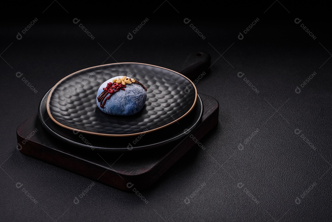 Deliciosas sobremesas mochi coloridas ou sorvete com massa de arroz e coberturas sobre um fundo escuro de concreto