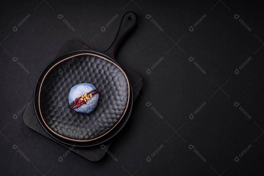 Deliciosas sobremesas mochi coloridas ou sorvete com massa de arroz e coberturas sobre um fundo escuro de concreto