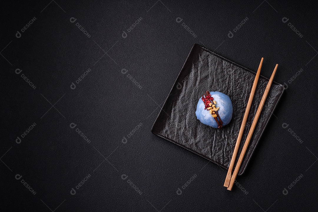 Deliciosas sobremesas mochi coloridas ou sorvete com massa de arroz e coberturas sobre um fundo escuro de concreto