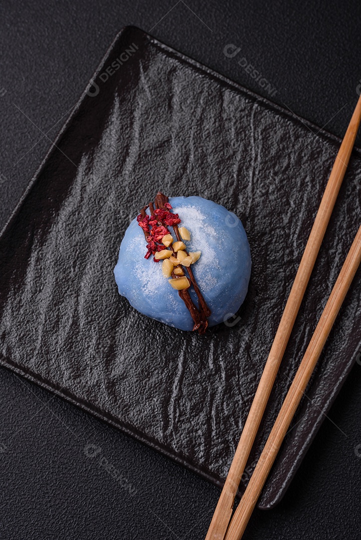 Deliciosas sobremesas mochi coloridas ou sorvete com massa de arroz e coberturas sobre um fundo escuro de concreto