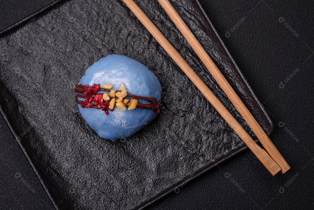 Deliciosas sobremesas mochi coloridas ou sorvete com massa de arroz e coberturas sobre um fundo escuro de concreto