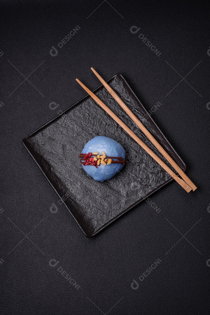 Deliciosas sobremesas mochi coloridas ou sorvete com massa de arroz e coberturas sobre um fundo escuro de concreto