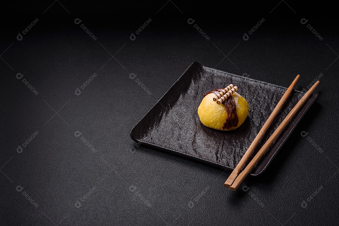 Deliciosas sobremesas mochi coloridas ou sorvete com massa de arroz e coberturas sobre um fundo escuro de concreto