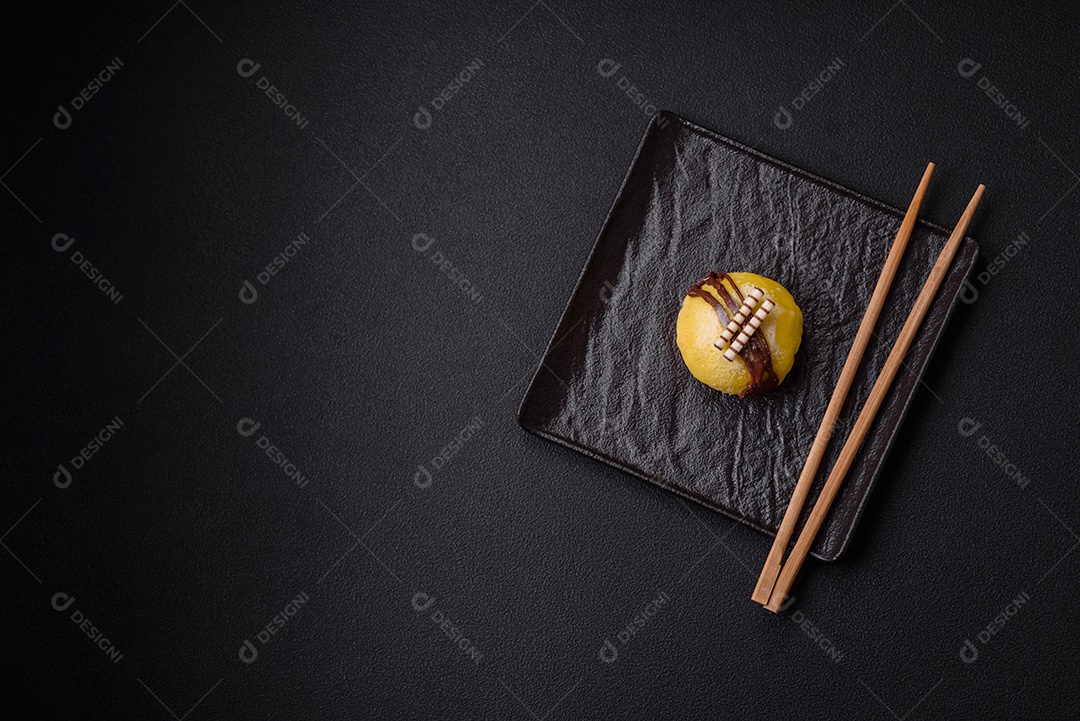 Deliciosas sobremesas mochi coloridas ou sorvete com massa de arroz e coberturas sobre um fundo escuro de concreto