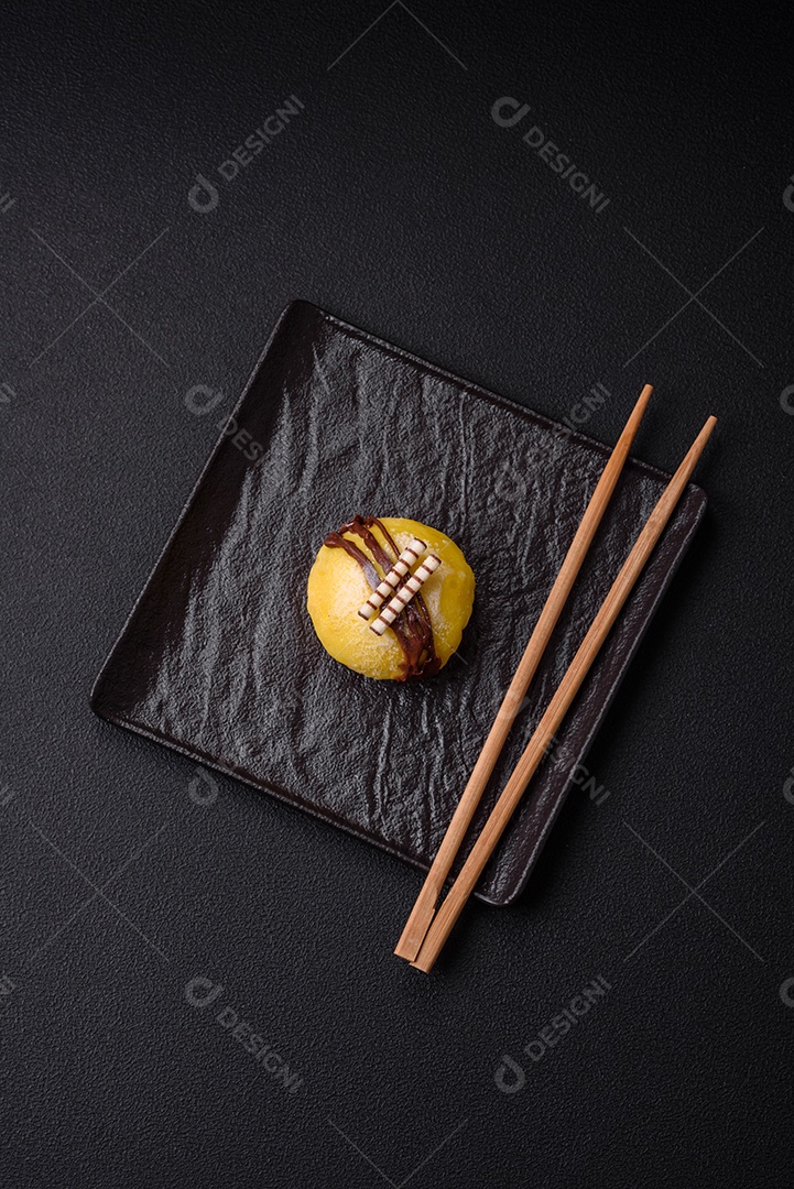 Deliciosas sobremesas mochi coloridas ou sorvete com massa de arroz e coberturas sobre um fundo escuro de concreto