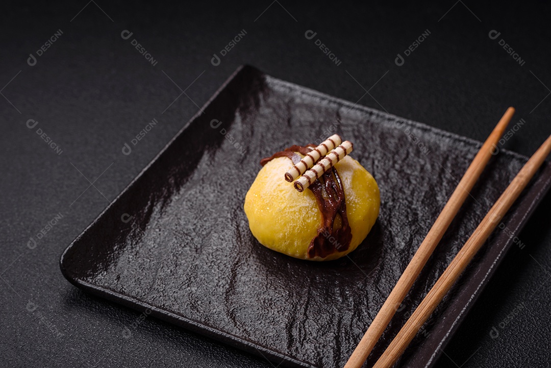 Deliciosas sobremesas mochi coloridas ou sorvete com massa de arroz e coberturas sobre um fundo escuro de concreto