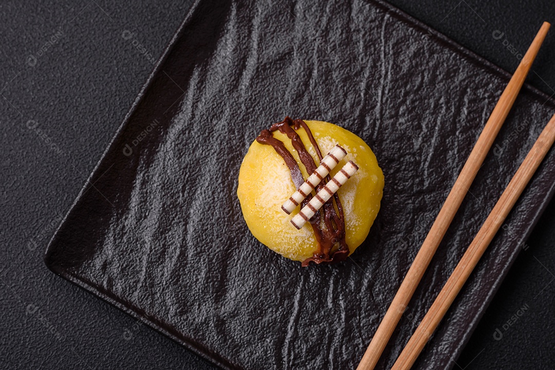 Deliciosas sobremesas mochi coloridas ou sorvete com massa de arroz e coberturas sobre um fundo escuro de concreto