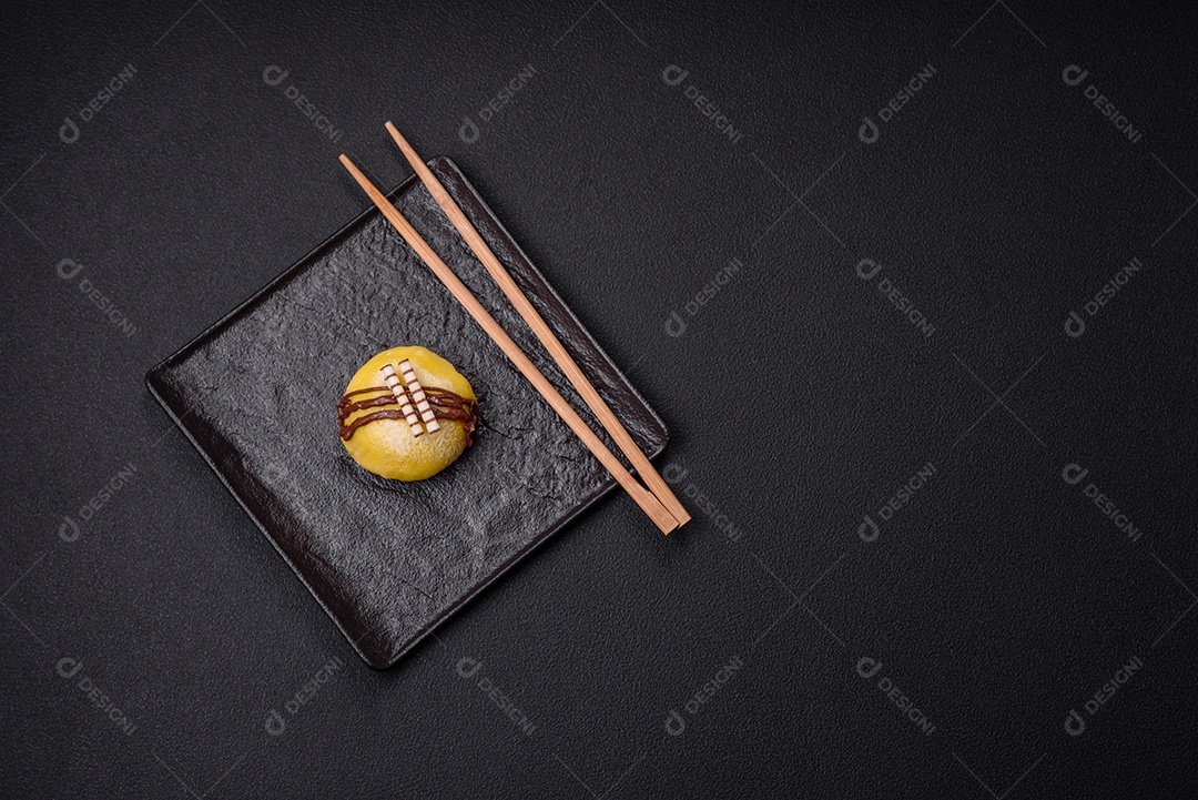 Deliciosas sobremesas mochi coloridas ou sorvete com massa de arroz e coberturas sobre um fundo escuro de concreto