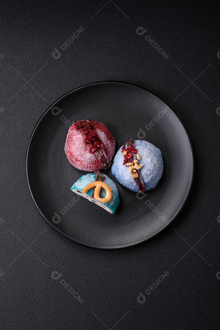Deliciosas sobremesas mochi coloridas ou sorvete com massa de arroz e coberturas sobre um fundo escuro de concreto