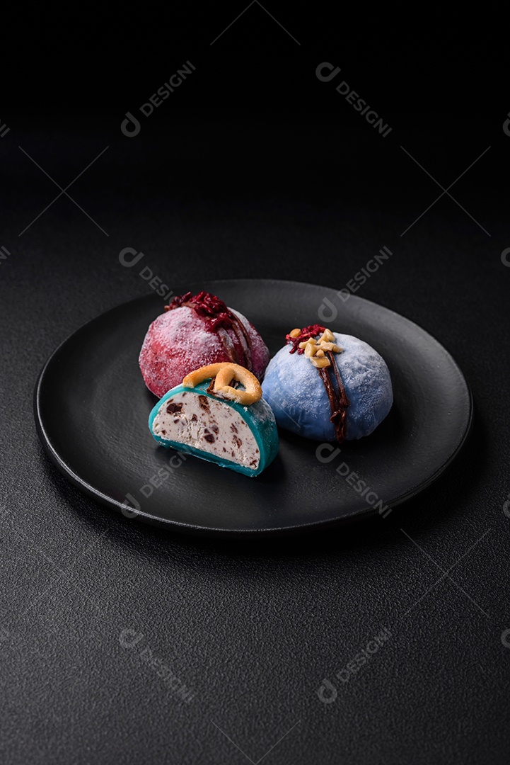 Deliciosas sobremesas mochi coloridas ou sorvete com massa de arroz e coberturas sobre um fundo escuro de concreto