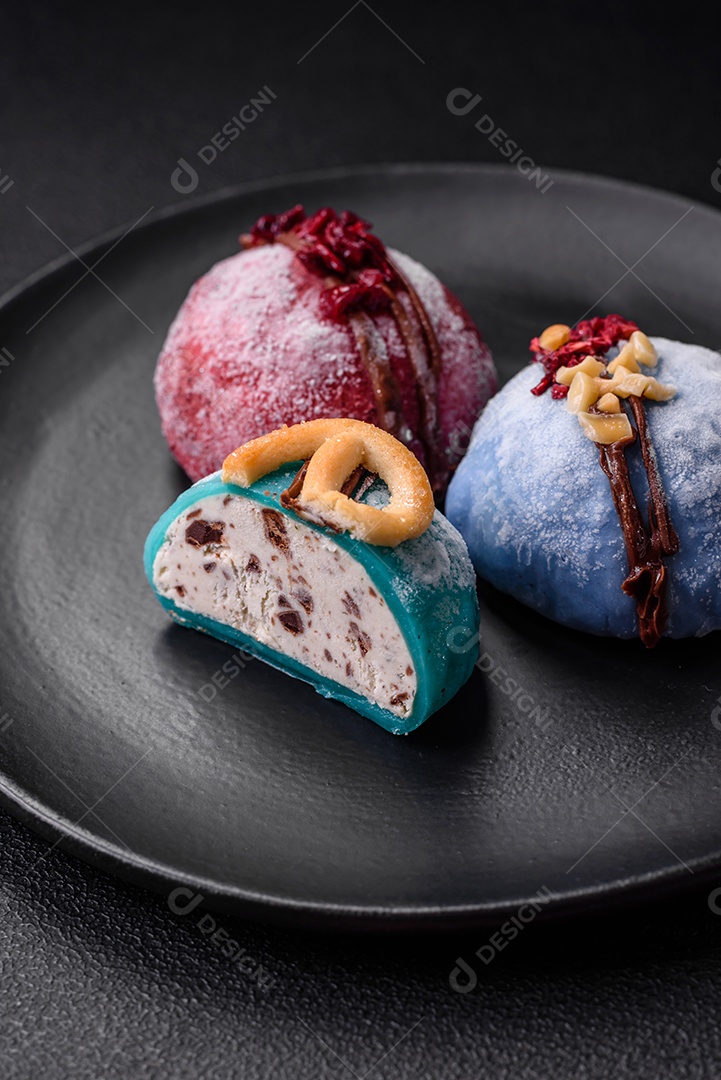 Deliciosas sobremesas mochi coloridas ou sorvete com massa de arroz e coberturas sobre um fundo escuro de concreto