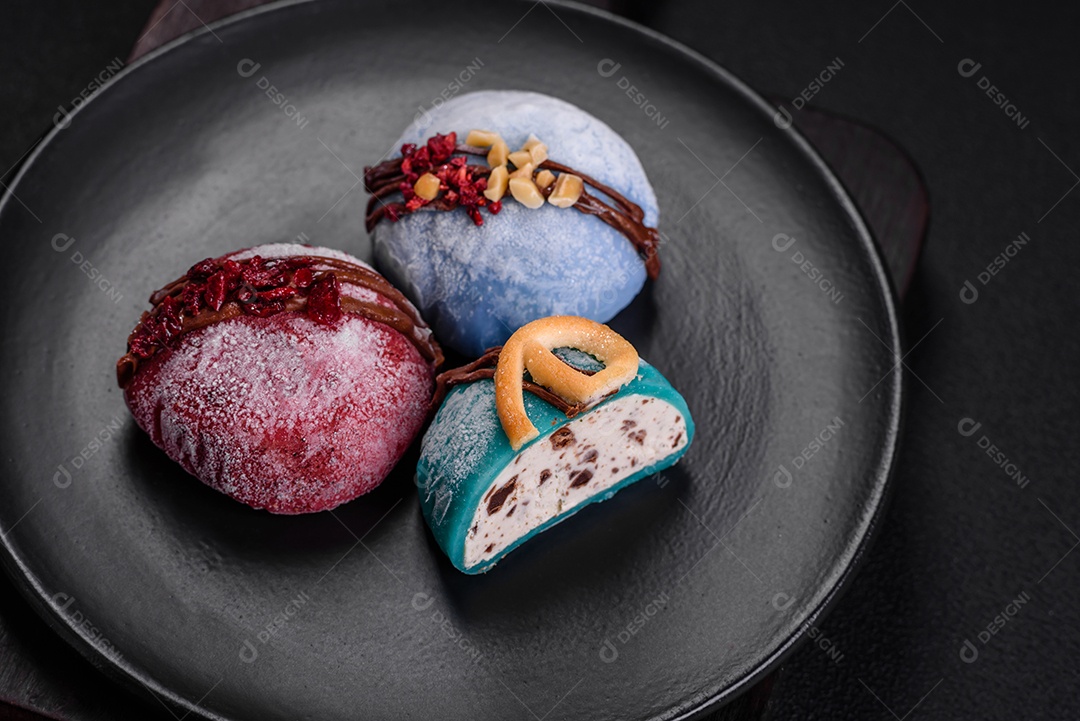 Deliciosas sobremesas mochi coloridas ou sorvete com massa de arroz e coberturas sobre um fundo escuro de concreto