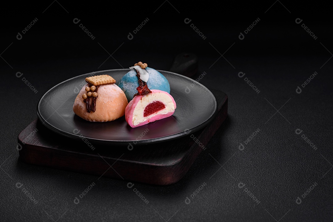 Deliciosas sobremesas mochi coloridas ou sorvete com massa de arroz e coberturas sobre um fundo escuro de concreto