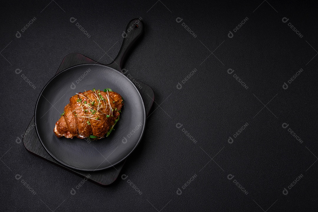 Delicioso croissant crocante com salmão, alface, queijo e tomate em um fundo escuro de concreto
