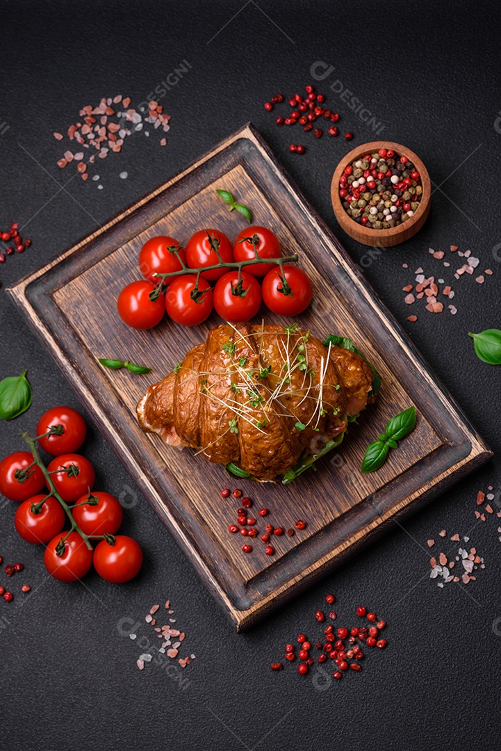 Delicioso croissant crocante com salmão, alface, queijo e tomate em um fundo escuro de concreto