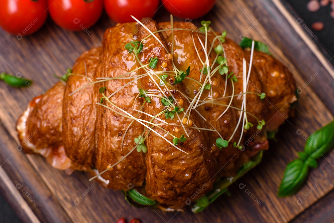 Delicioso croissant crocante com salmão, alface, queijo e tomate em um fundo escuro de concreto