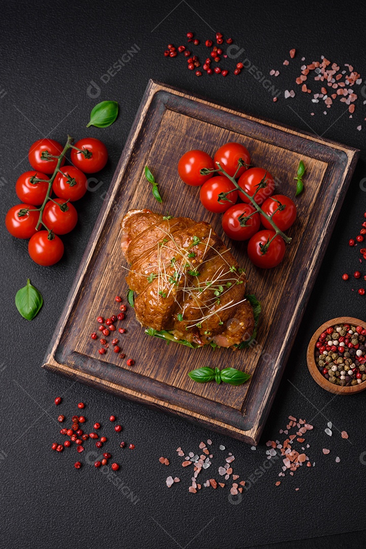 Delicioso croissant crocante com salmão, alface, queijo e tomate em um fundo escuro de concreto