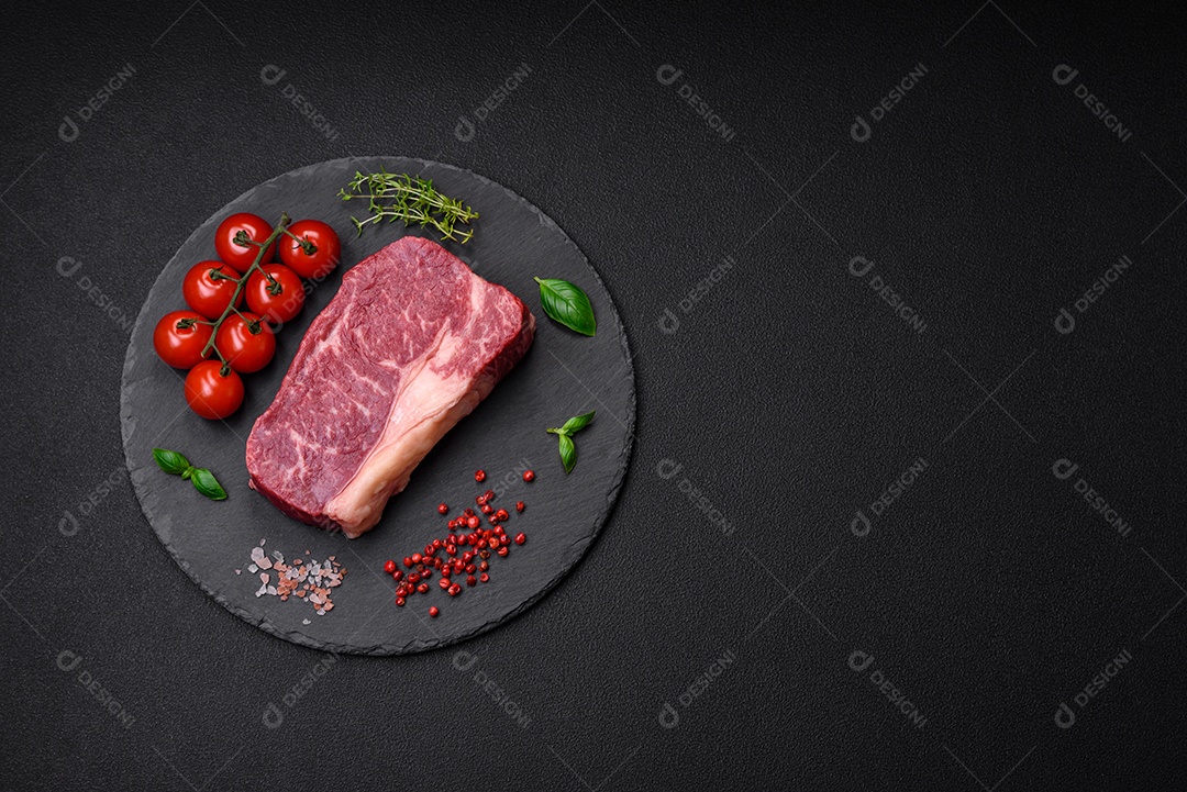 Bife de carne crua fresca com sal, especiarias e ervas sobre um fundo escuro de concreto