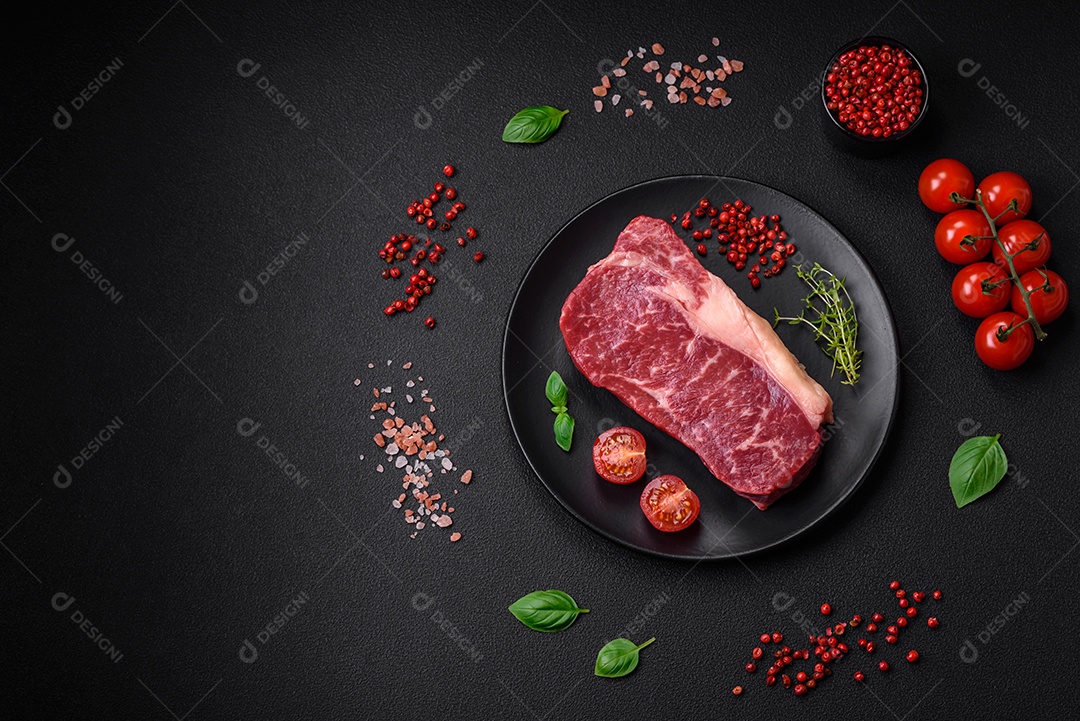 Bife de carne crua fresca com sal, especiarias e ervas sobre um fundo escuro de concreto
