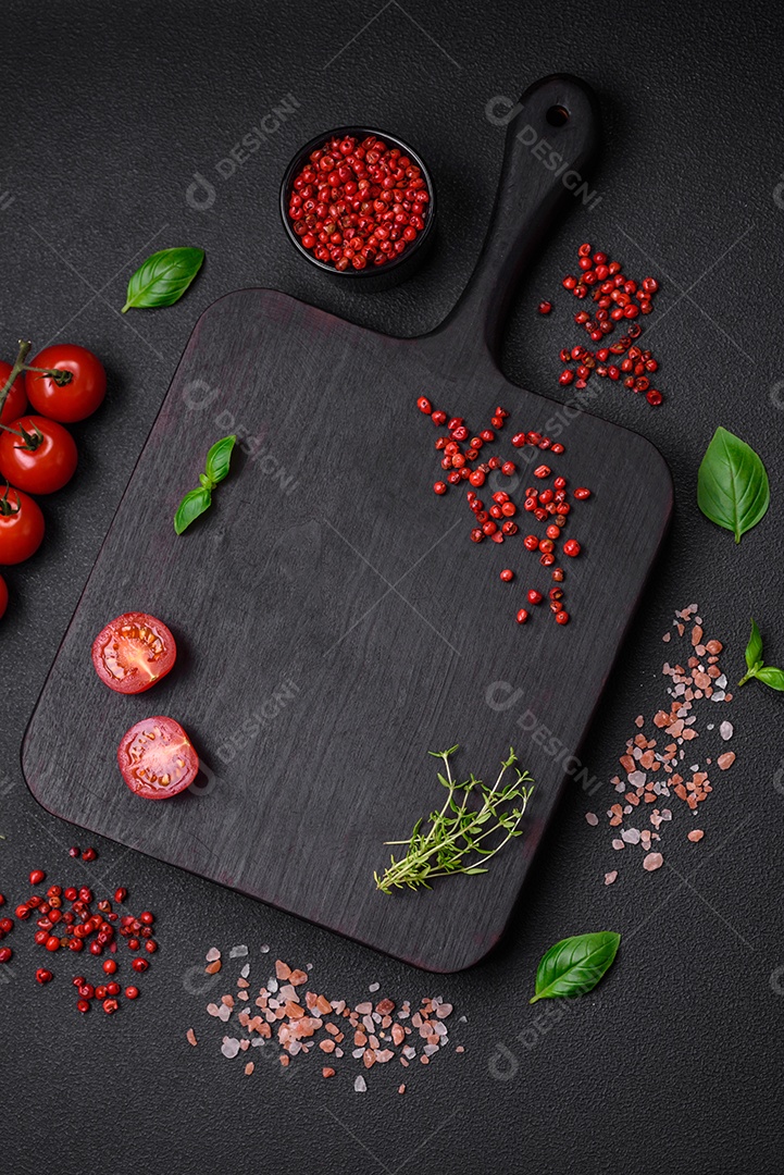 Ingredientes para cozinhar tomate cereja, sal, especiarias e ervas sobre um fundo escuro de concreto