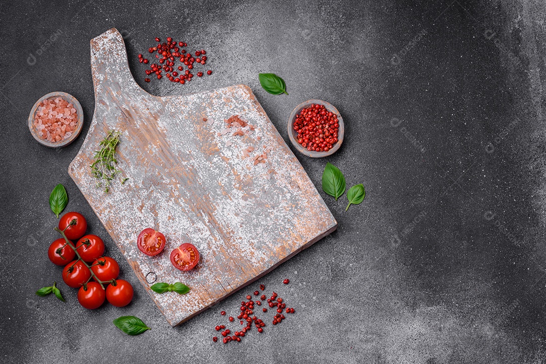 Ingredientes para cozinhar tomate cereja, sal, especiarias e ervas sobre um fundo escuro de concreto