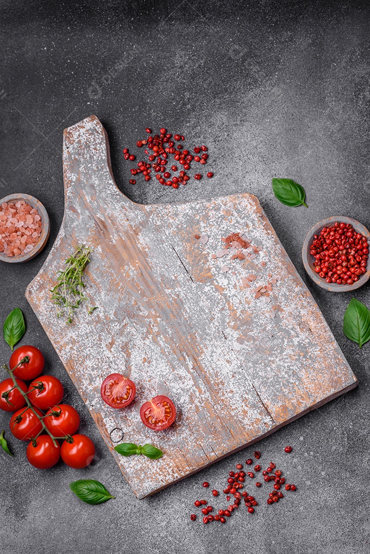 Ingredientes para cozinhar tomate cereja, sal, especiarias e ervas sobre um fundo escuro de concreto