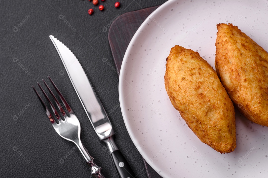Deliciosa costeleta de batata assada recheada com frango e legumes, especiarias e sal sobre um fundo escuro de concreto