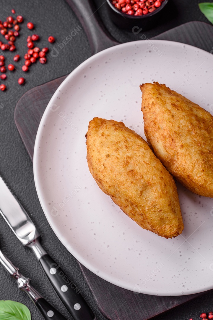 Deliciosa costeleta de batata assada recheada com frango e legumes, especiarias e sal sobre um fundo escuro de concreto