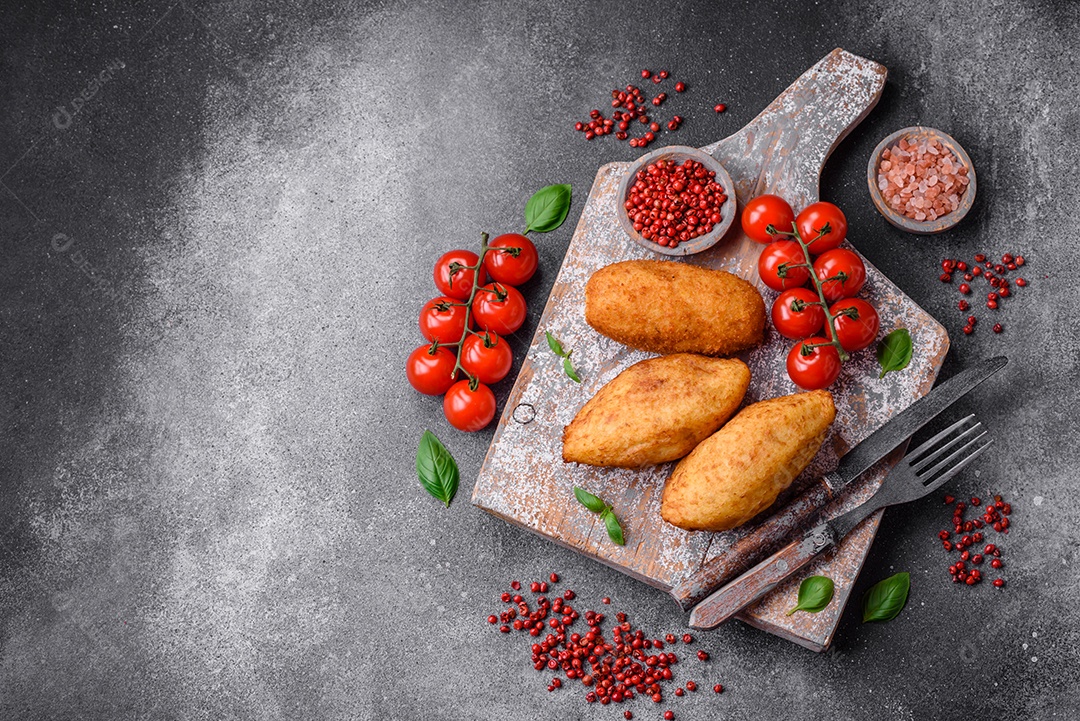 Deliciosa costeleta de batata assada recheada com frango e legumes, especiarias e sal sobre um fundo escuro de concreto