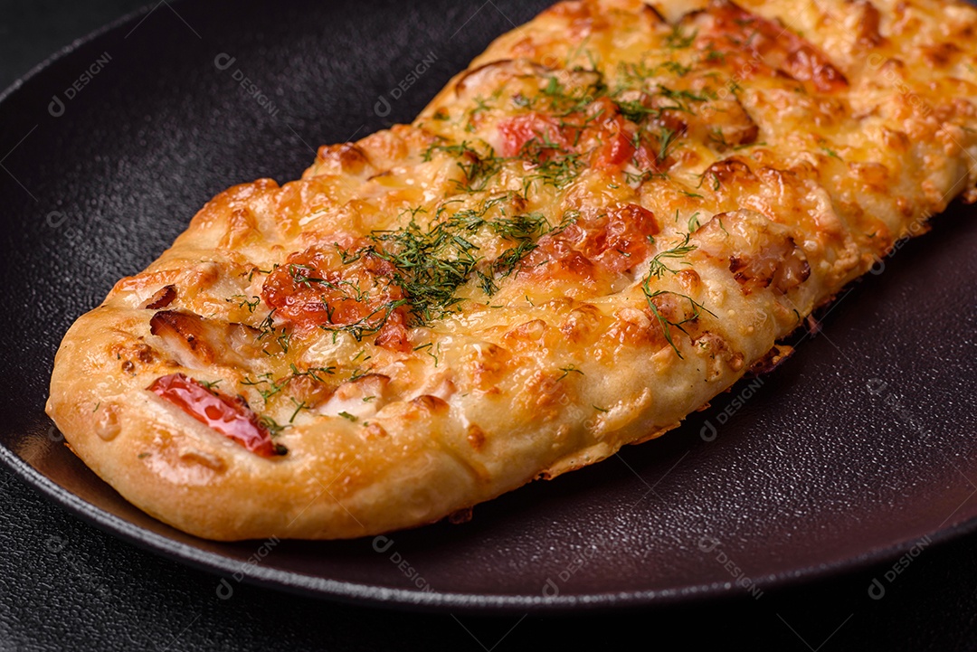 Deliciosa pizza de pão achatado fresco com queijo, tomate, salsicha, sal e especiarias sobre um fundo escuro de concreto