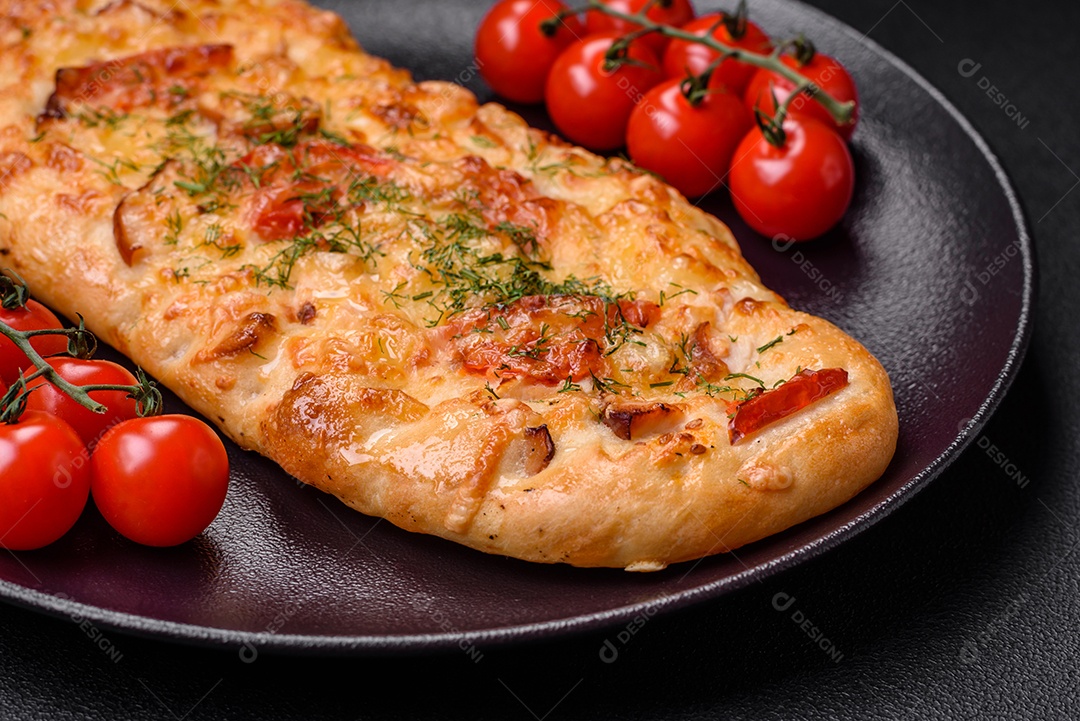 Deliciosa pizza de pão achatado fresco com queijo, tomate, salsicha, sal e especiarias sobre um fundo escuro de concreto