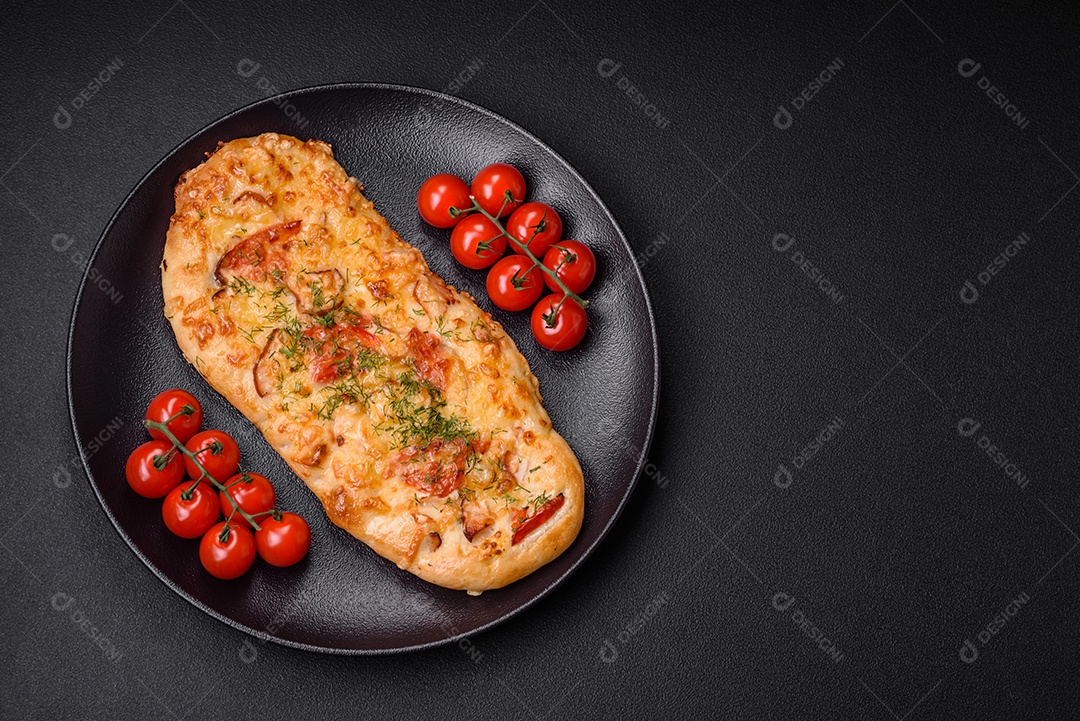 Deliciosa pizza de pão achatado fresco com queijo, tomate, salsicha, sal e especiarias sobre um fundo escuro de concreto