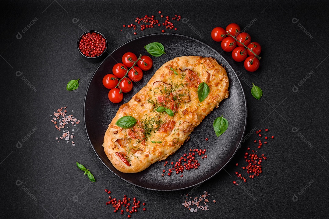 Deliciosa pizza de pão achatado fresco com queijo, tomate, salsicha, sal e especiarias sobre um fundo escuro de concreto