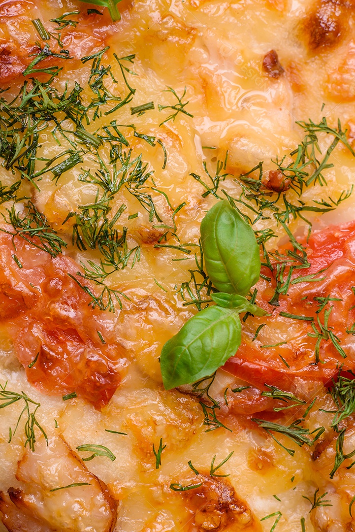 Deliciosa pizza de pão achatado fresco com queijo, tomate, salsicha, sal e especiarias sobre um fundo escuro de concreto