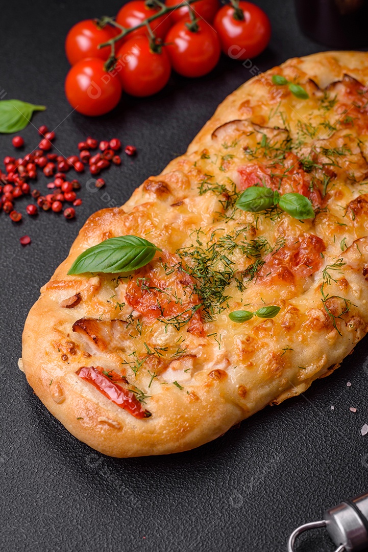Deliciosa pizza de pão achatado fresco com queijo, tomate, salsicha, sal e especiarias sobre um fundo escuro de concreto