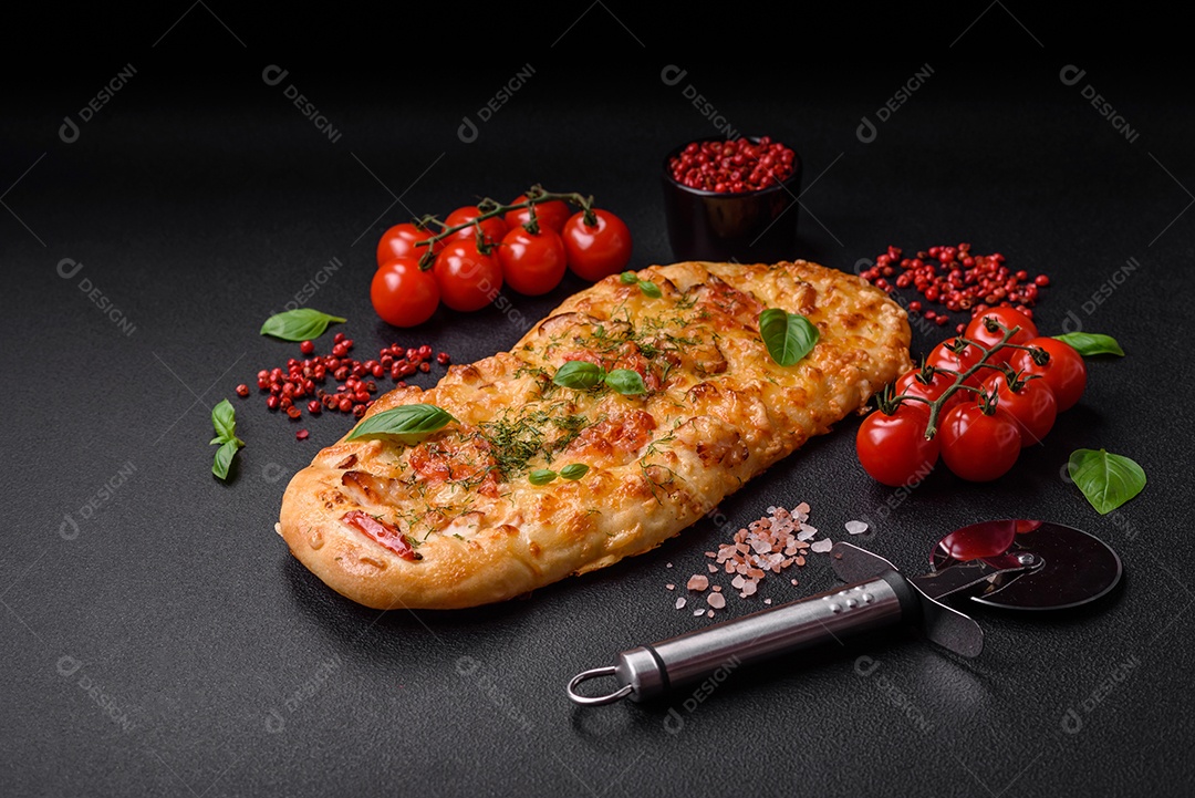 Deliciosa pizza de pão achatado fresco com queijo, tomate, salsicha, sal e especiarias sobre um fundo escuro de concreto