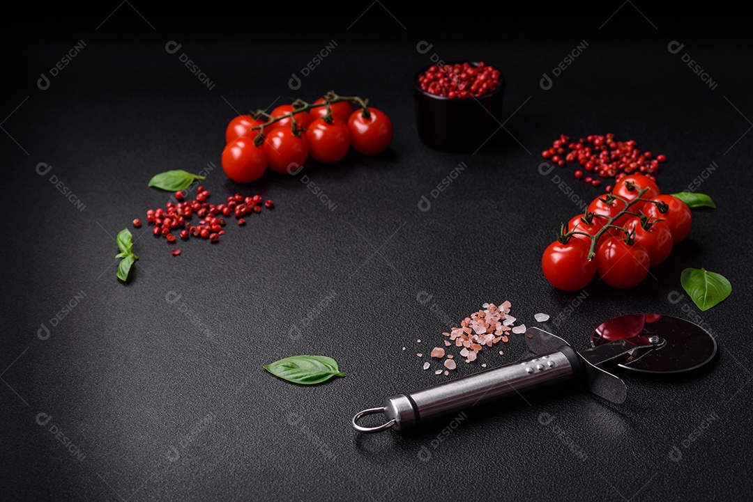 Ingredientes para cozinhar tomate cereja, sal, especiarias e ervas sobre um fundo escuro de concreto