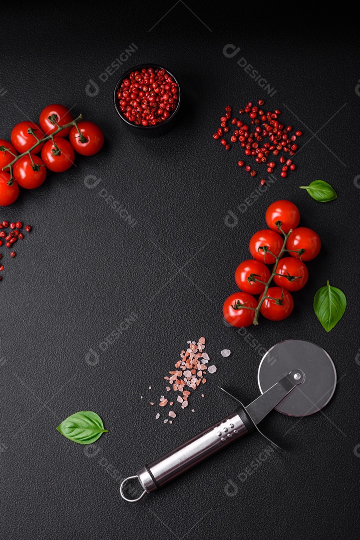 Ingredientes para cozinhar tomate cereja, sal, especiarias e ervas sobre um fundo escuro de concreto