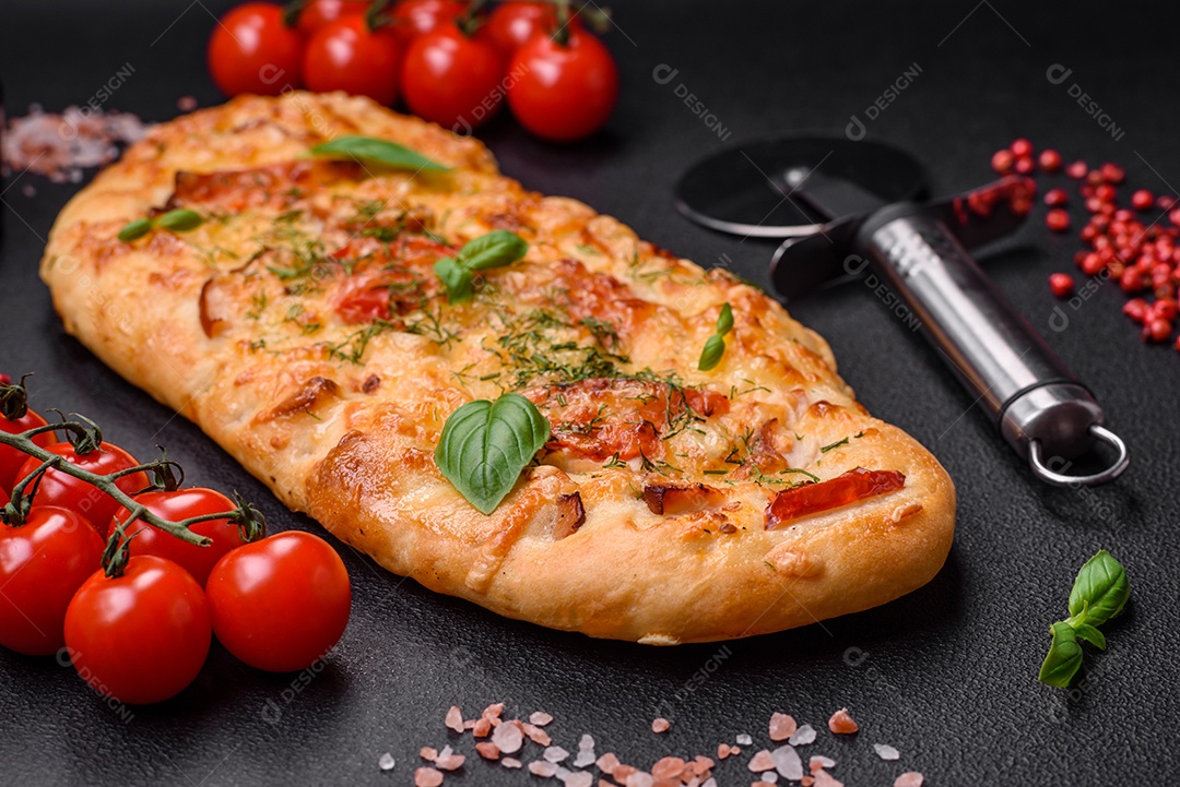 Deliciosa pizza de pão achatado fresco com queijo, tomate, salsicha, sal e especiarias sobre um fundo escuro de concreto