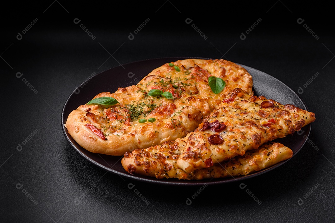 Deliciosa pizza de pão achatado fresco com queijo, tomate, salsicha, sal e especiarias sobre um fundo escuro de concreto
